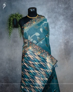 Teal blue tissue silk saree with floral leaf motifs, broad woven border and multicolour pallu