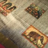 Charcoal Grey Silk Saree with Mughal Prints and Floral Emboss Work Charcoal grey silk saree with Mughal-inspired art, floral emboss work, multicolour panels and zari border