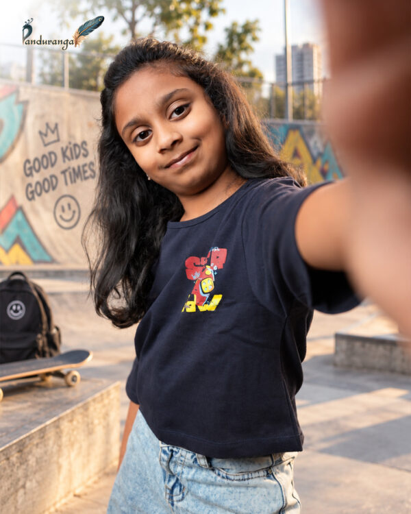Blue crop T-shirt for girls with colourful front and back graphic prints, paired with light blue jeans.