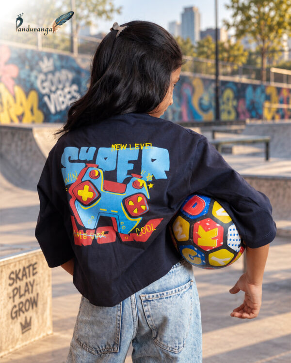 Blue crop T-shirt for girls with colourful front and back graphic prints, paired with light blue jeans.